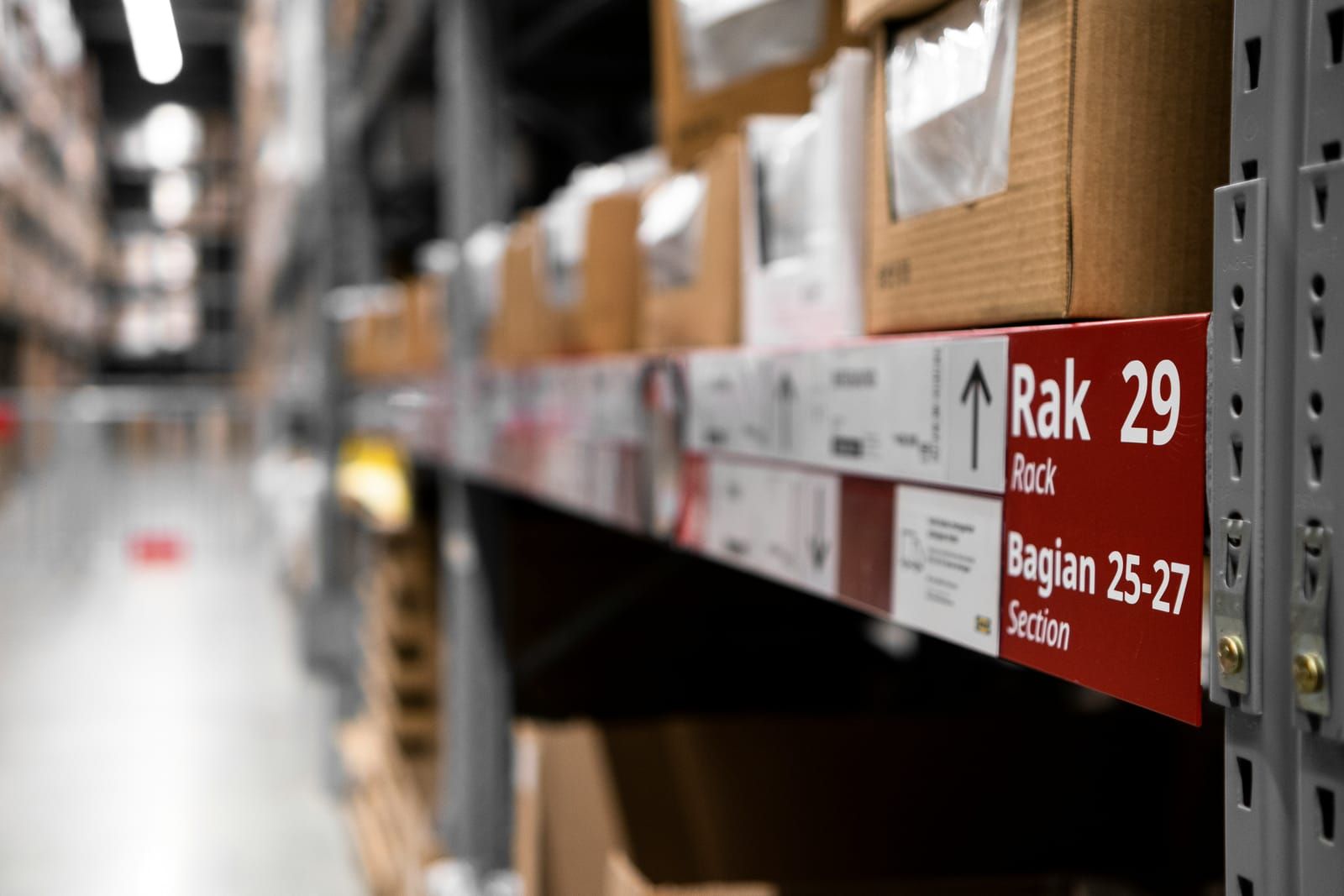 Warehouse shelving stacked with boxes, with a red location label for rack 29, sections 25â27, in focus.